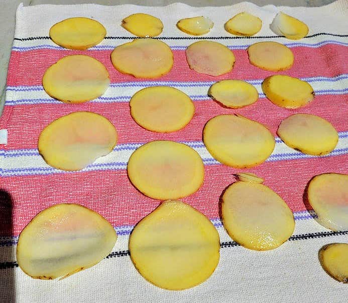 pat dry potato slices on a kitchen towel
