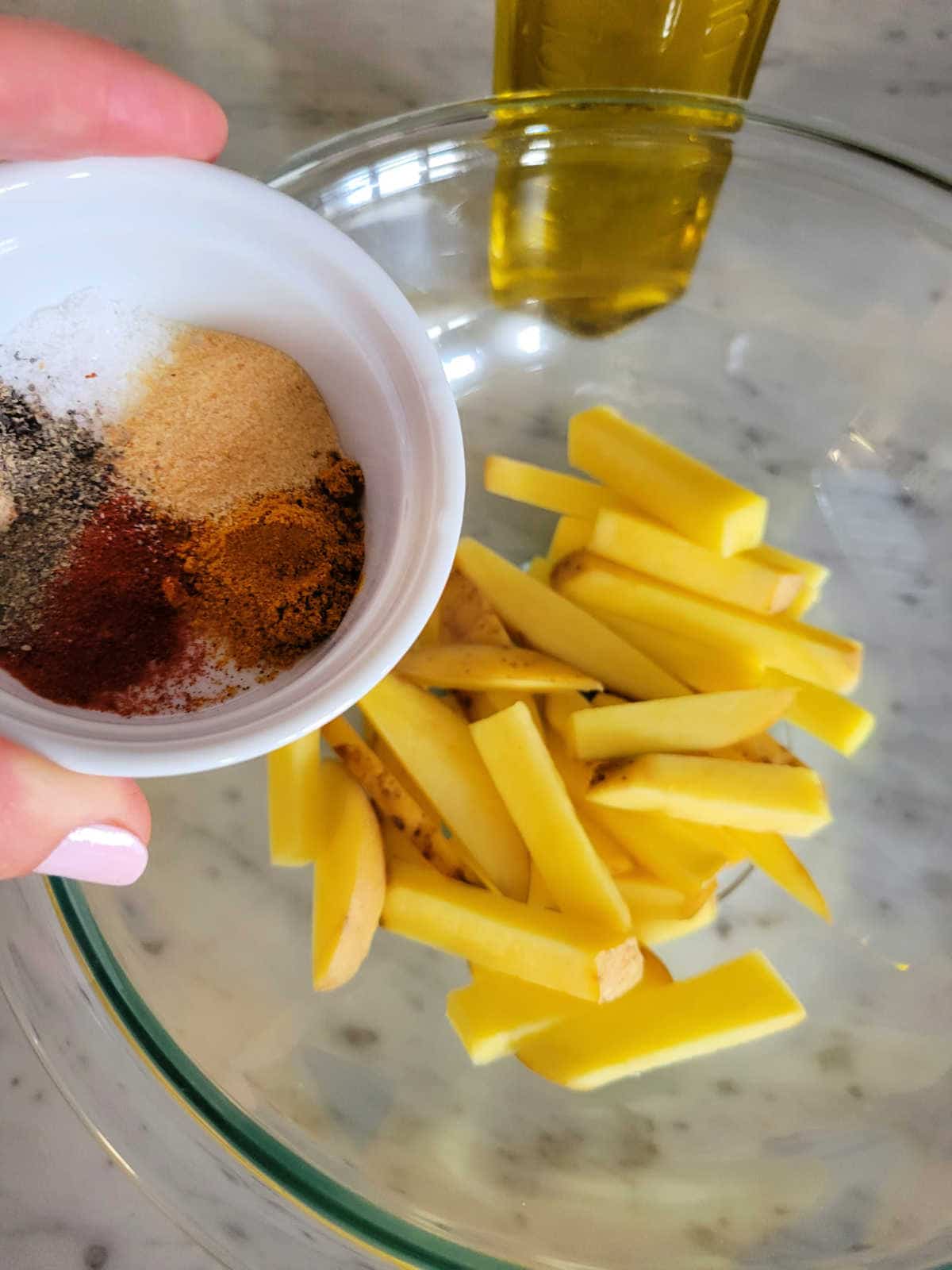 potato cut up into fries with oil and seasoning