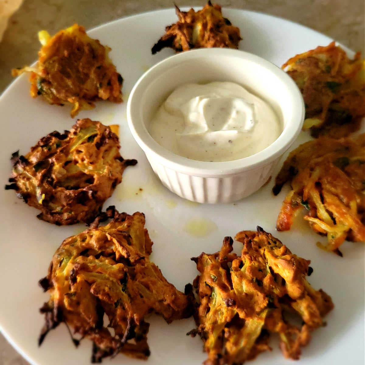 onion fritters on a plate with a dipping sauce