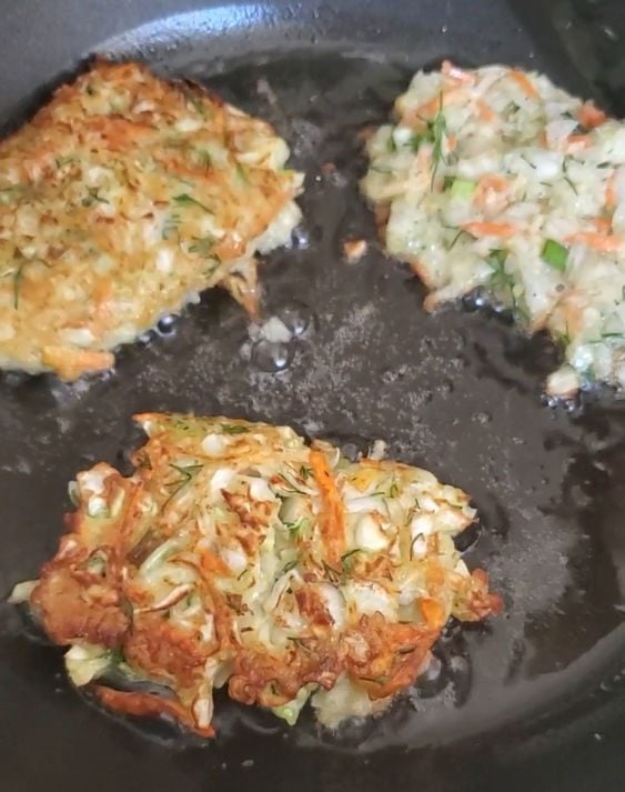 golden cabbage pancakes in a skillet with a thin layer of oil