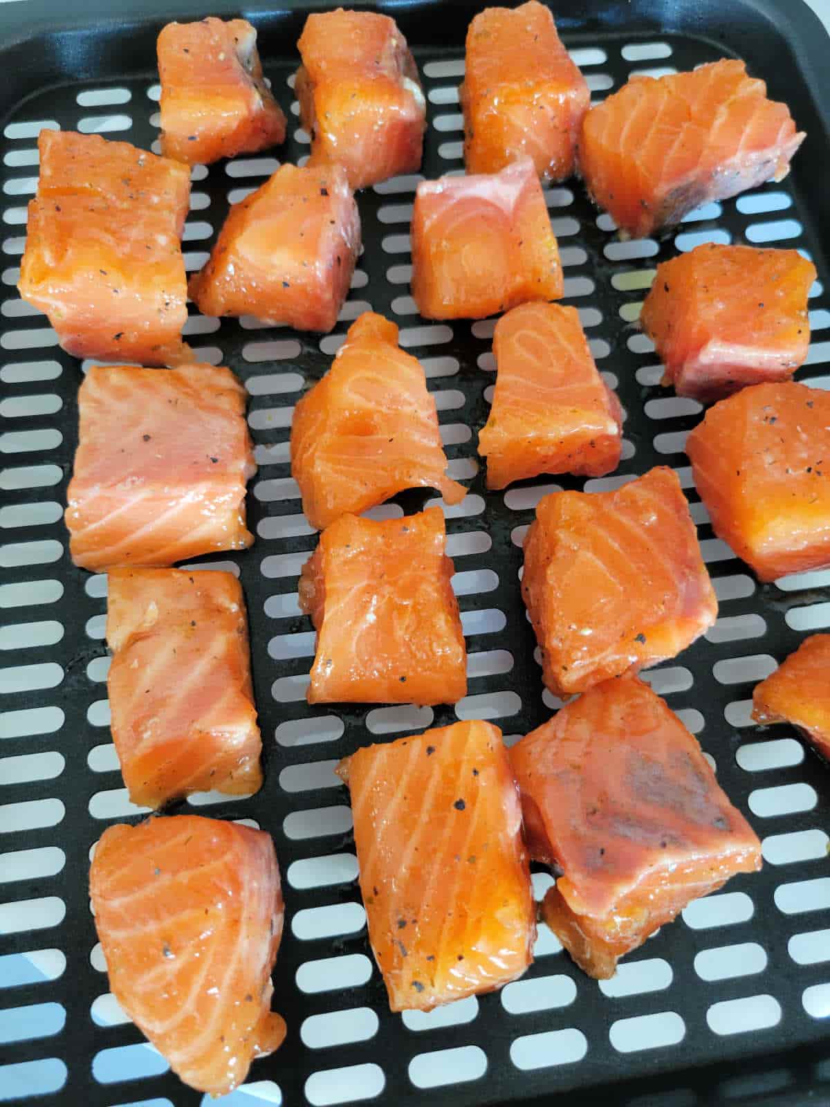 raw salmon cubes spaced out in air fryer basket