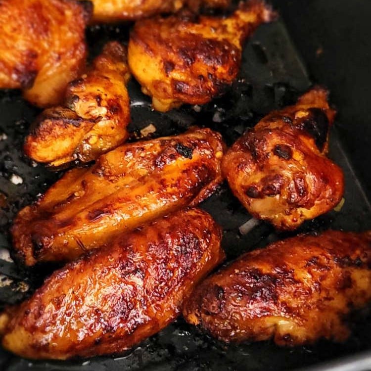 chicken wings with golden charred skin in air fryer basket