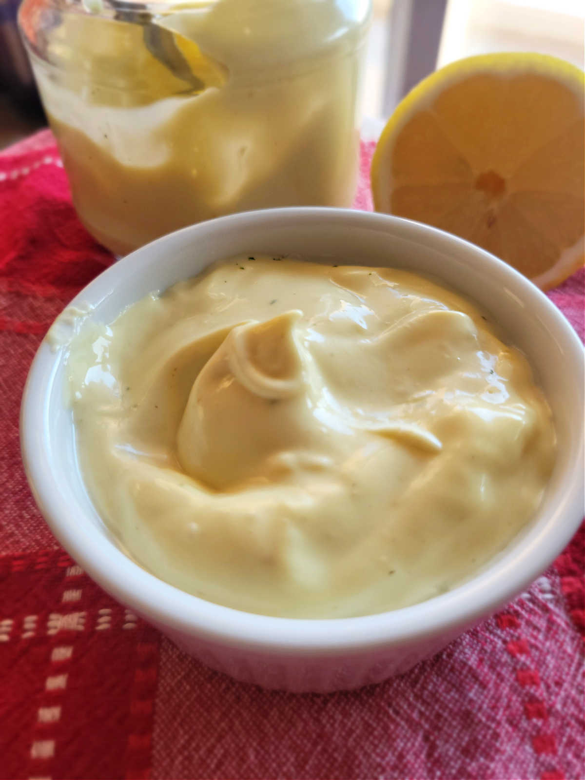 A bowl of creamy homemade mayonnaise with a glass jar, showing its smooth, rich texture – a delicious alternative to store-bought mayo